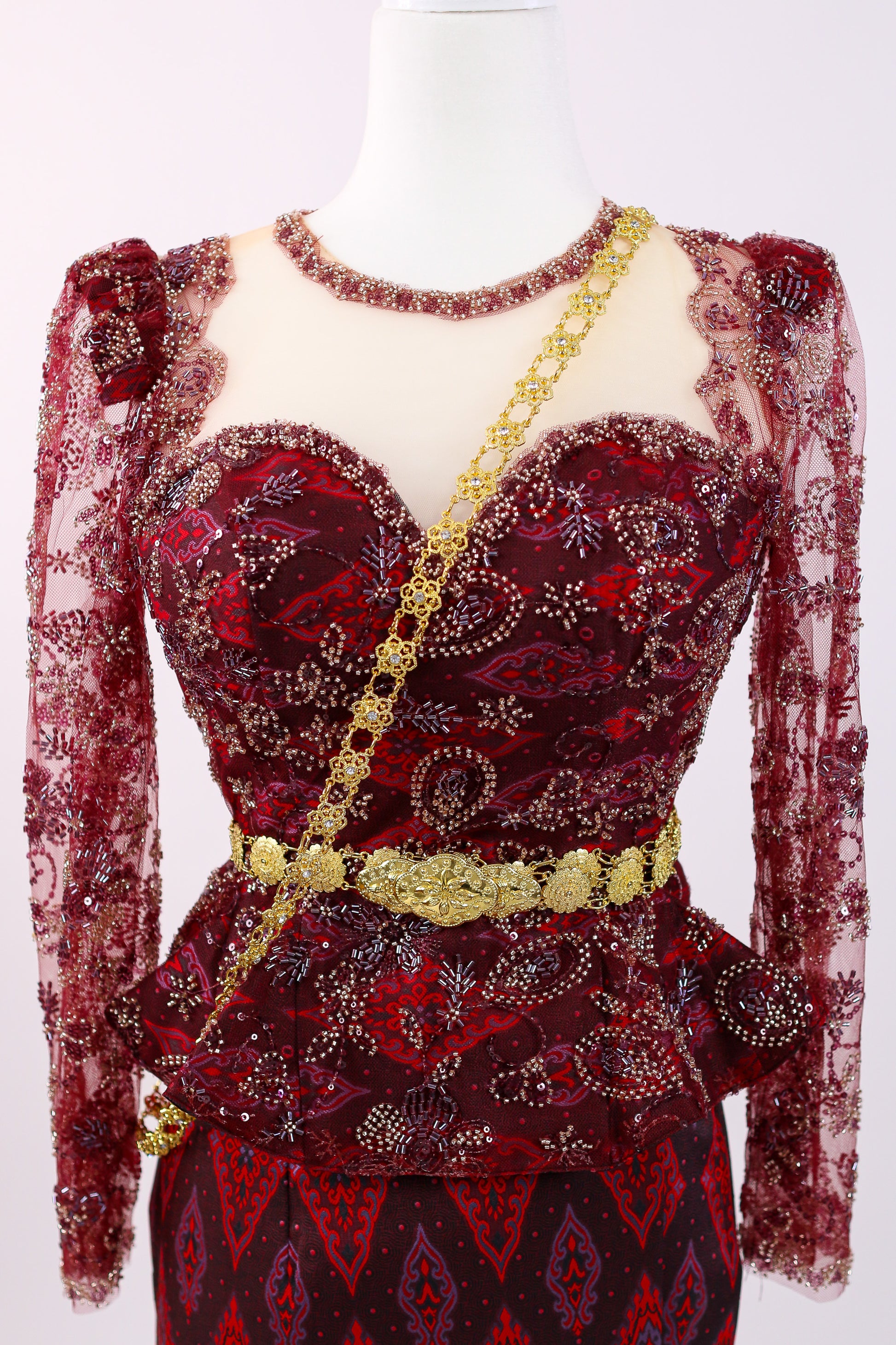 Red patterned dress with gold accents on a mannequin against a white background