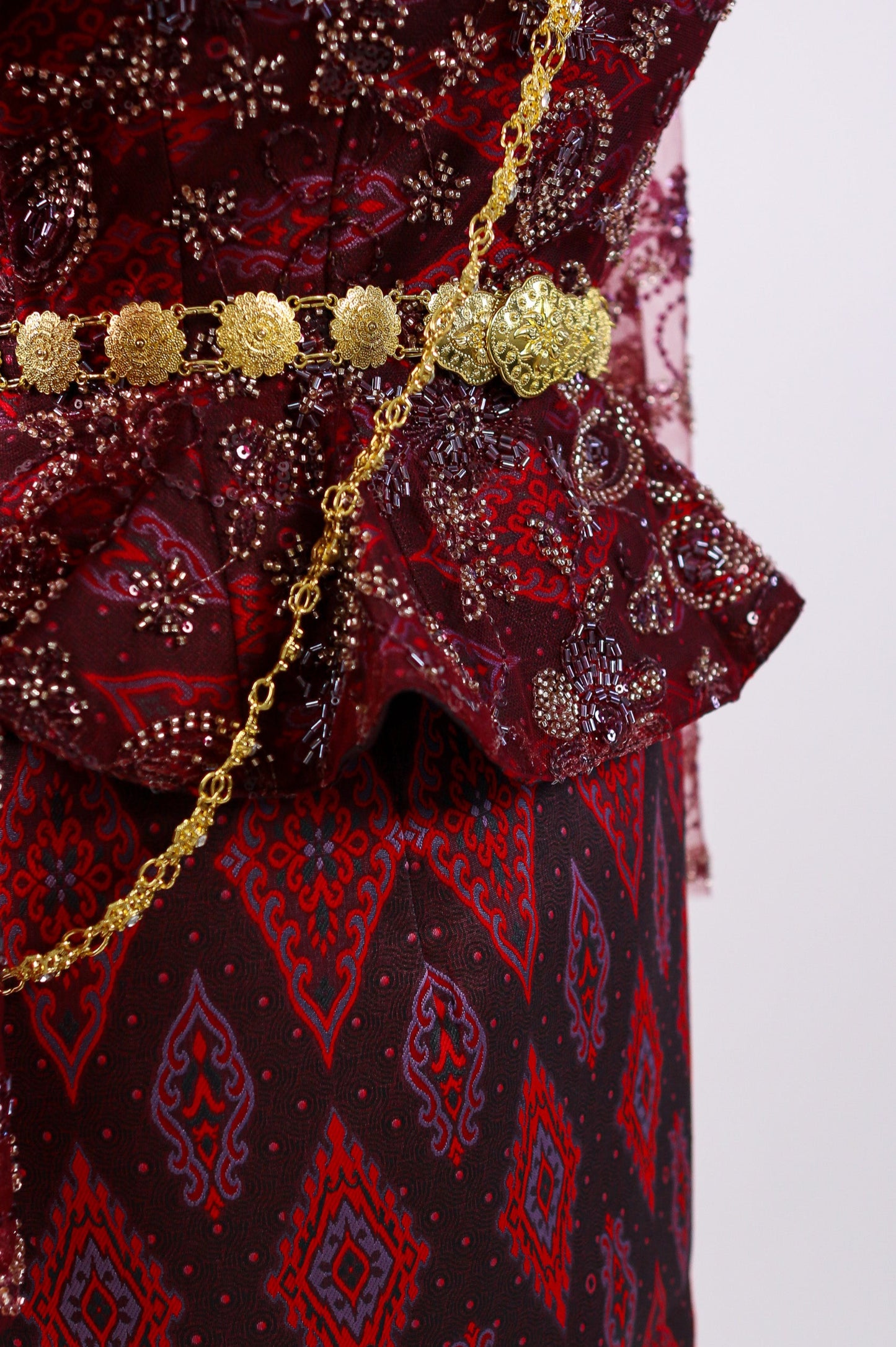 Red patterned garment with a gold belt on a white background