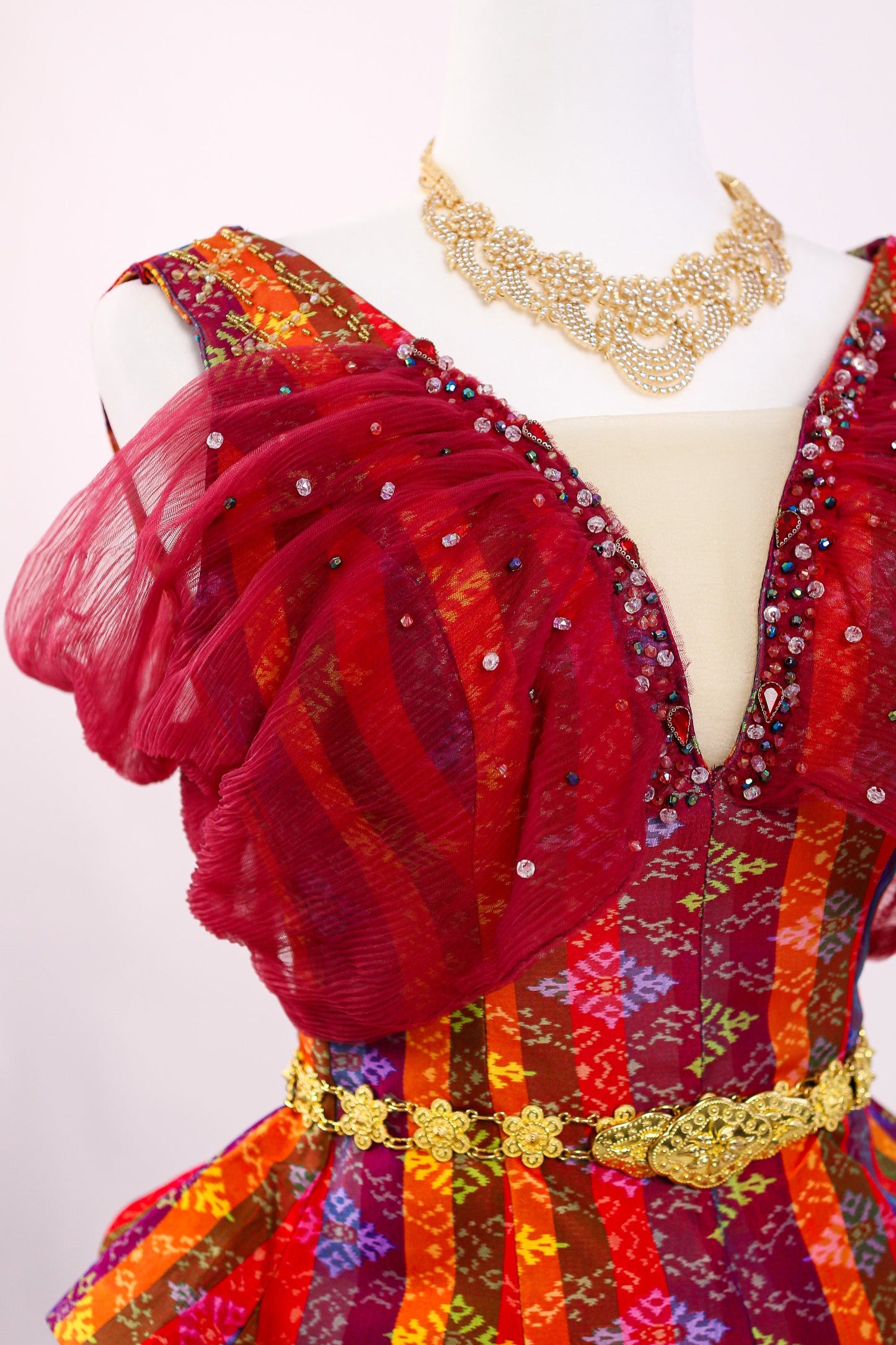 Colorful dress with gold accents on a mannequin against a white background