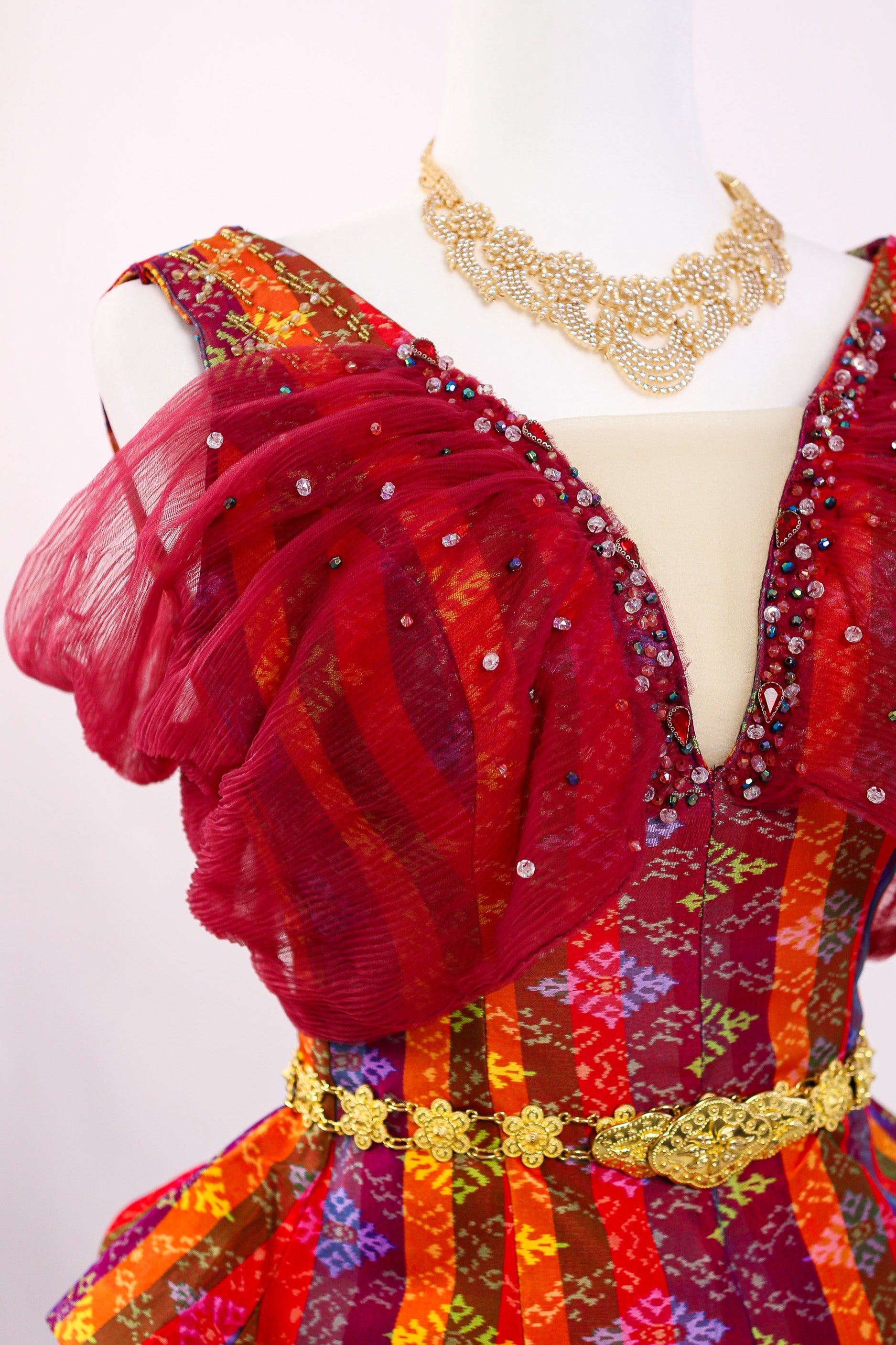 Colorful dress with gold accents on a mannequin against a white background