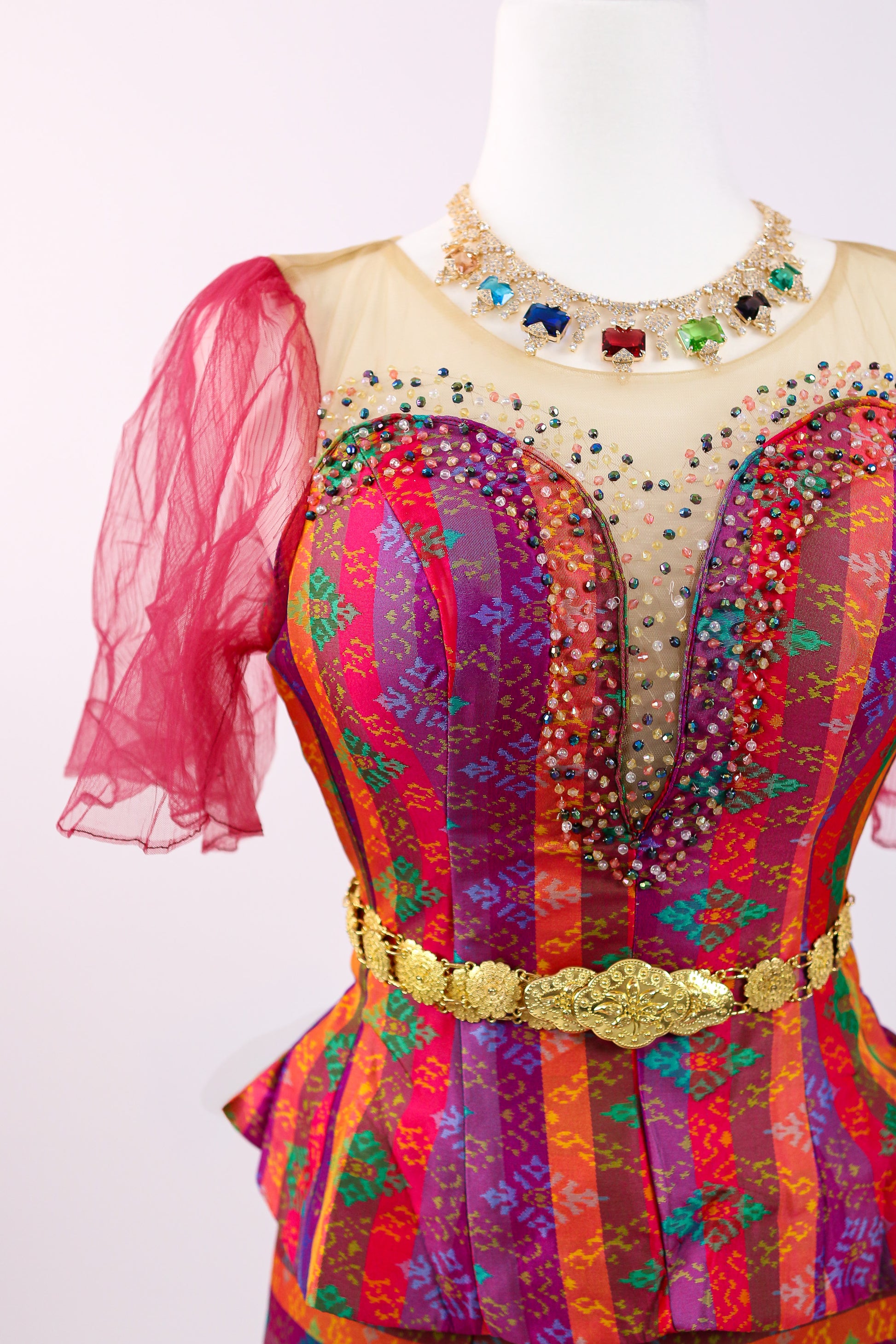 Colorful dress with intricate patterns and embellishments on a mannequin against a white background