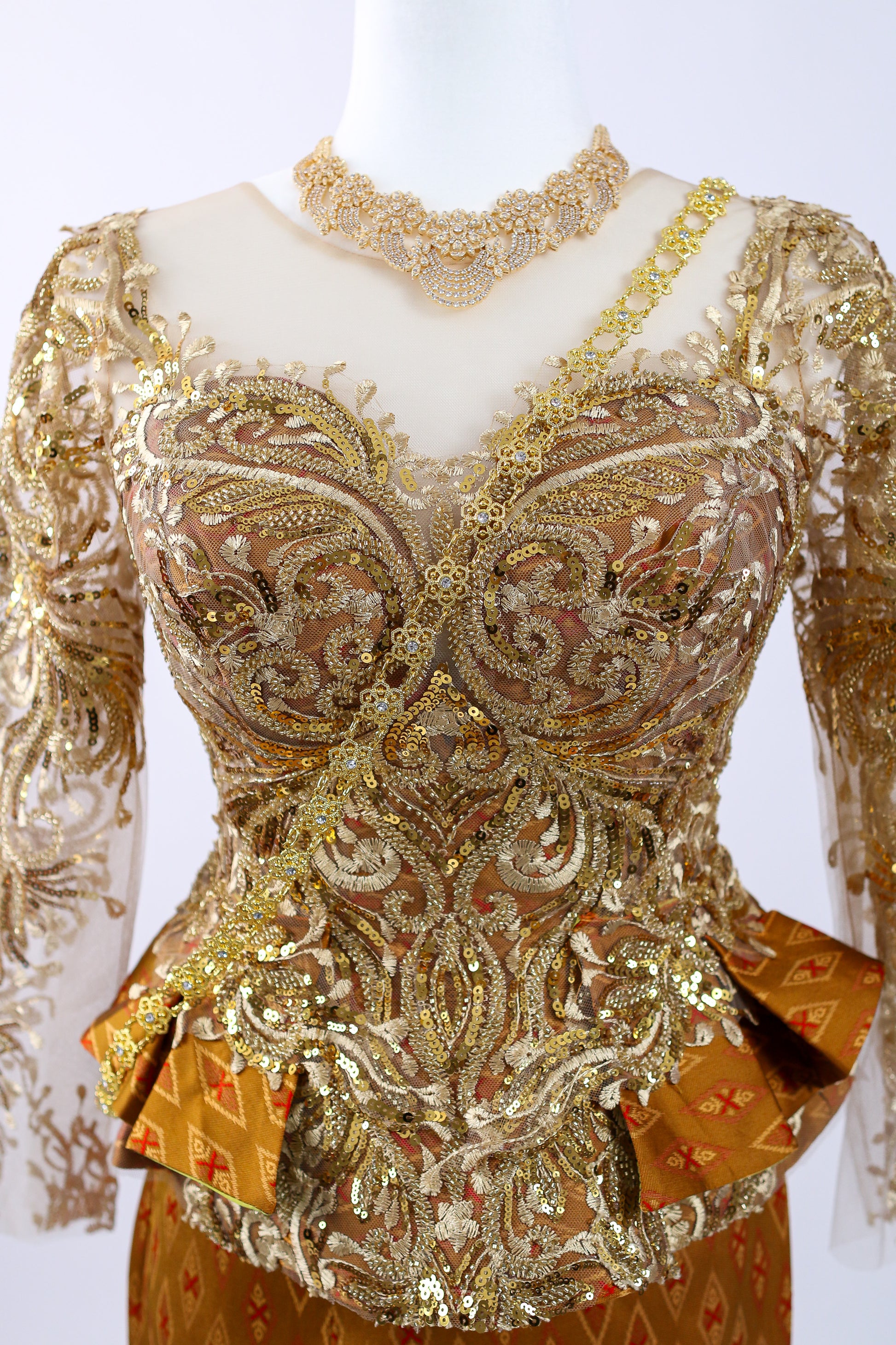Decorative top with intricate gold embroidery on a white background